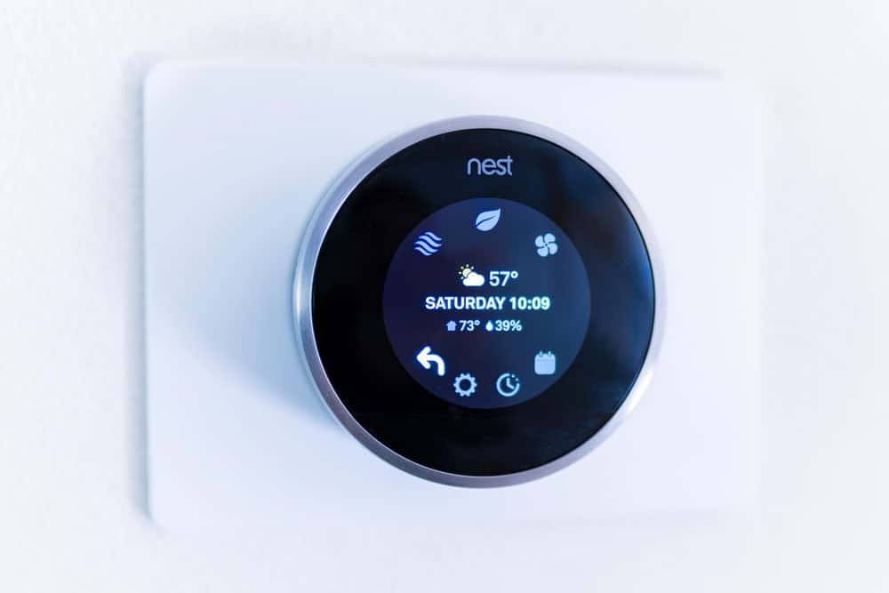 A nest smart thermostat is displayed on a wall.