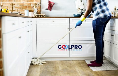 A woman cleaning a kitchen with a mop.