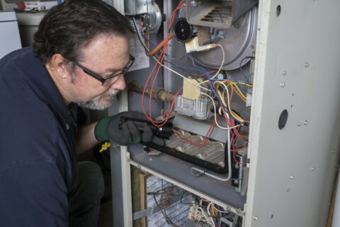A man is working on a furnace.