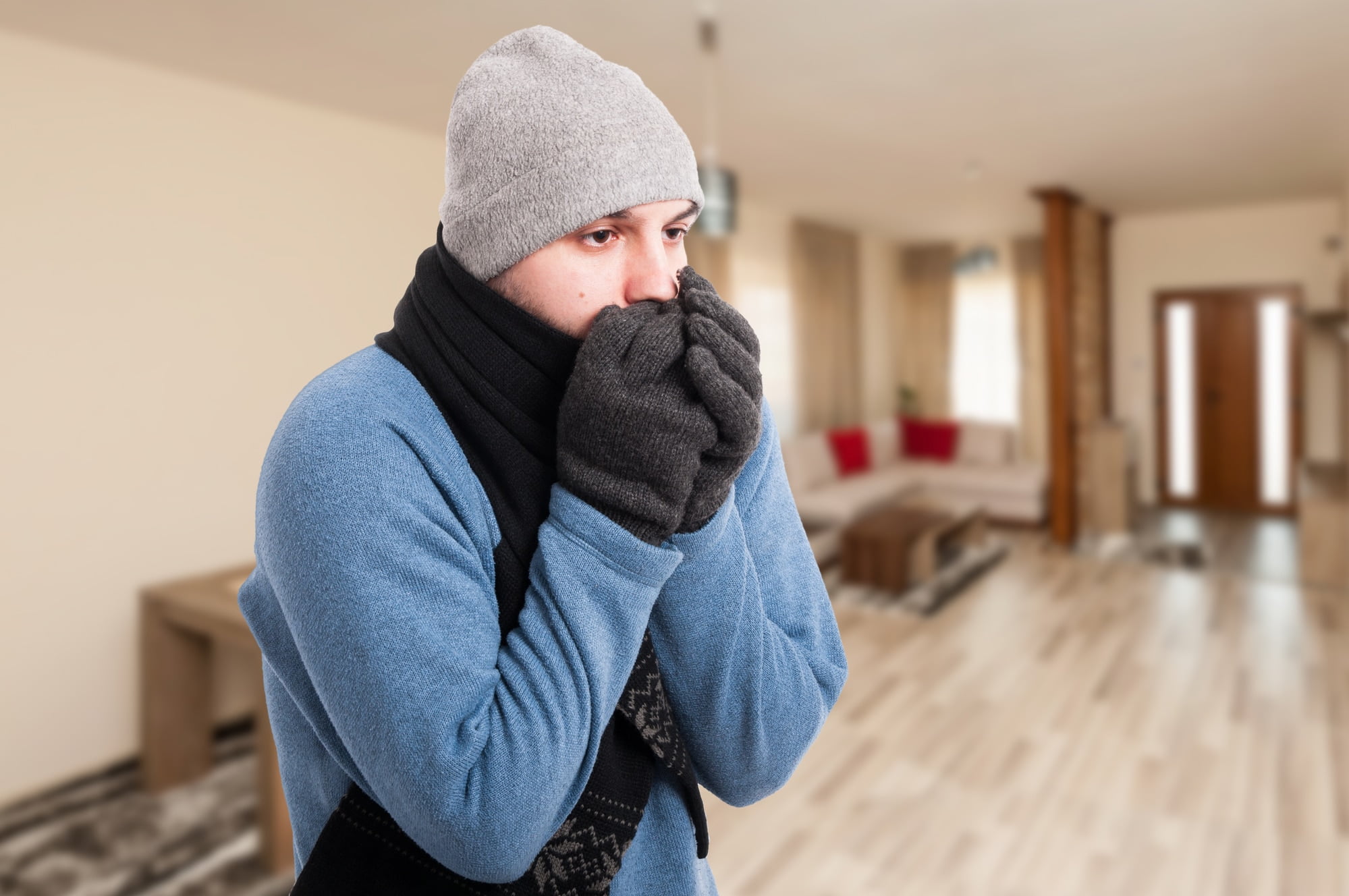 A man with a scarf covering his face in a living room.