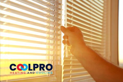 A person opening a window blind with the words coolpro heating and air conditioning.