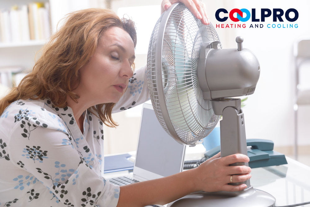 A woman looking at a fan on her desk.