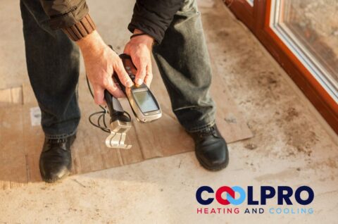 A man is holding a cell phone in front of a window.