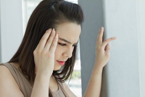 A woman with a headache is holding her hand to her head.