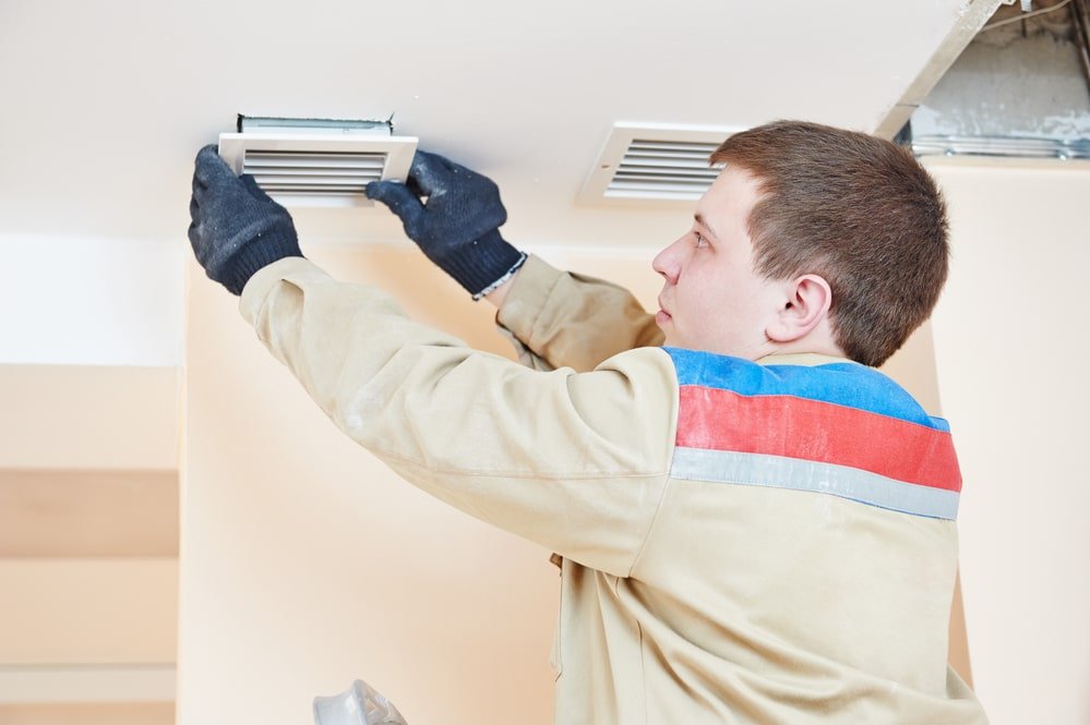 A man installing a ceiling fan in a room.