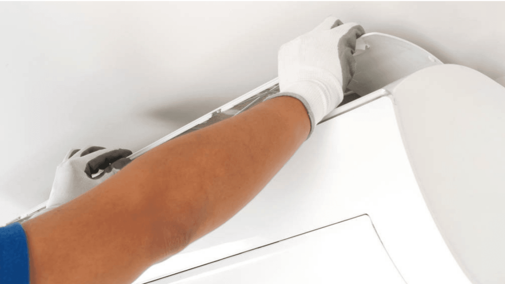 A person in blue gloves is fixing a white air conditioner.