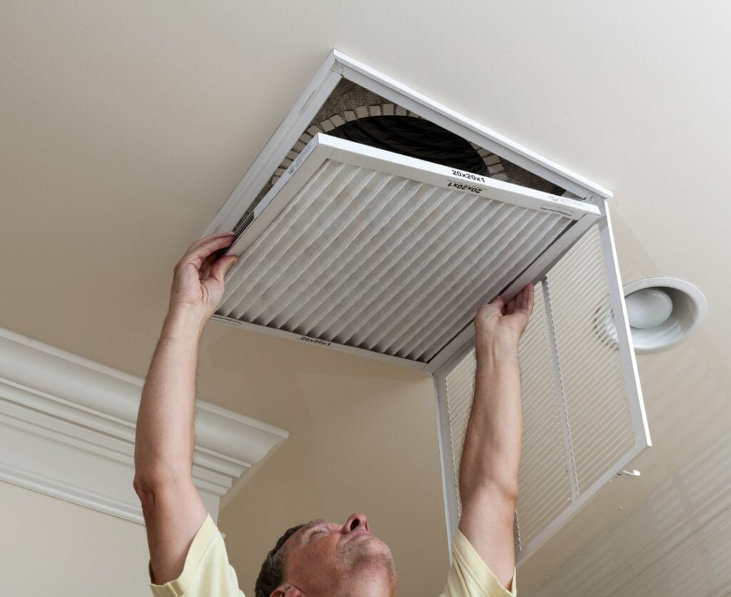 A man fixing an air conditioner in a room.