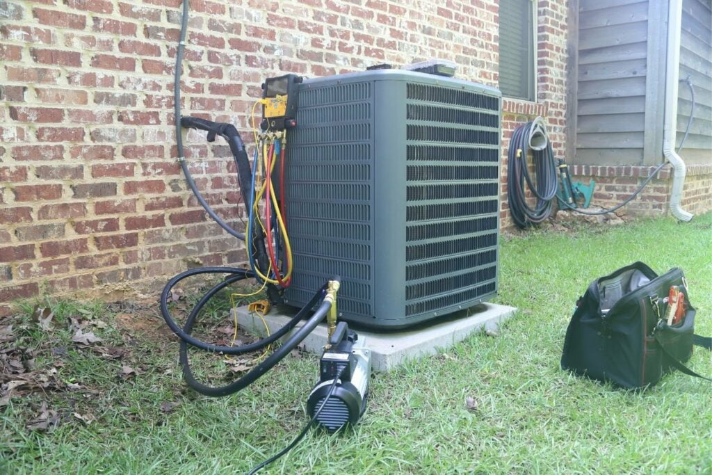 An air conditioner is sitting on the grass next to a building.