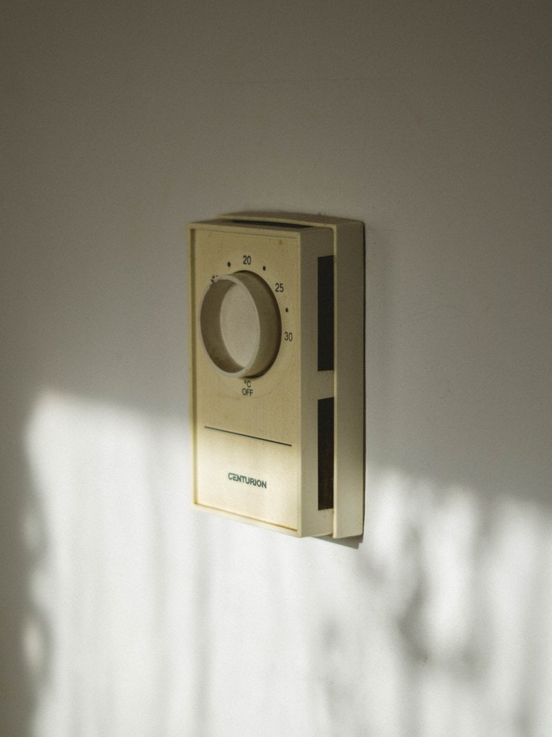 A wall mounted thermostat in a white room.