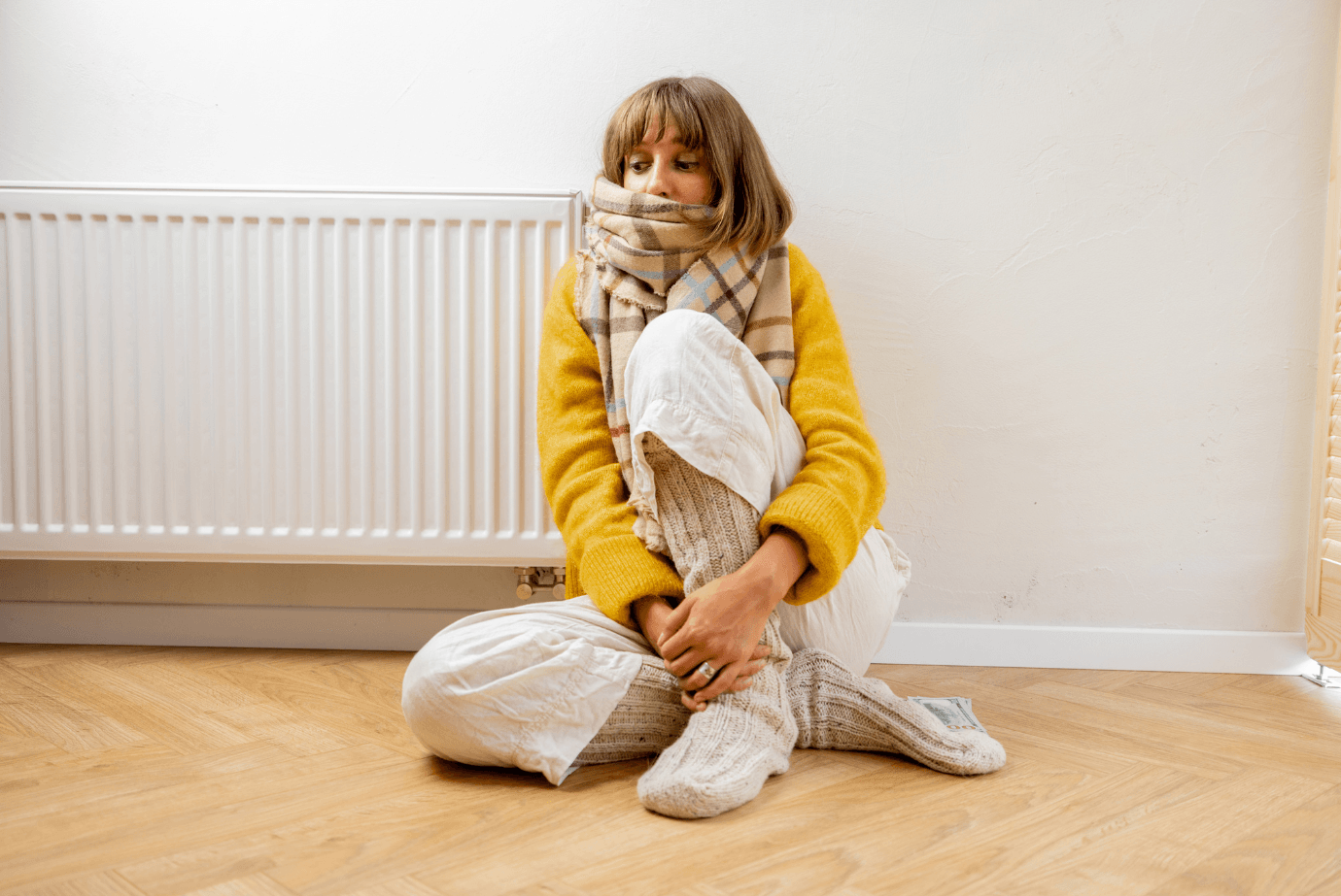 A woman sitting on the floor next to a radiator.