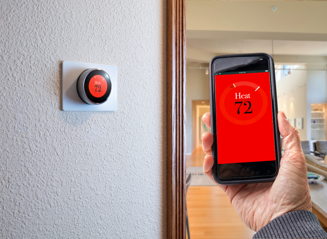 A person holding a smart thermostat.