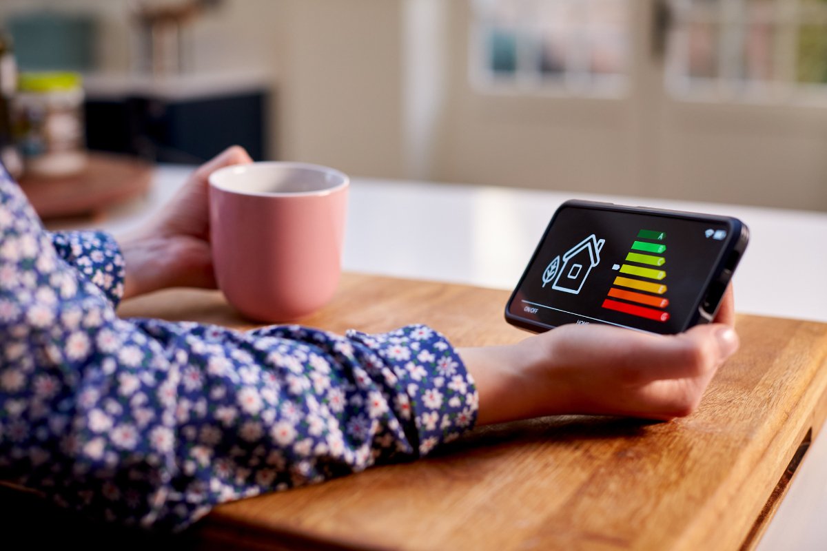 A woman is holding a smartphone with an energy graph on it.