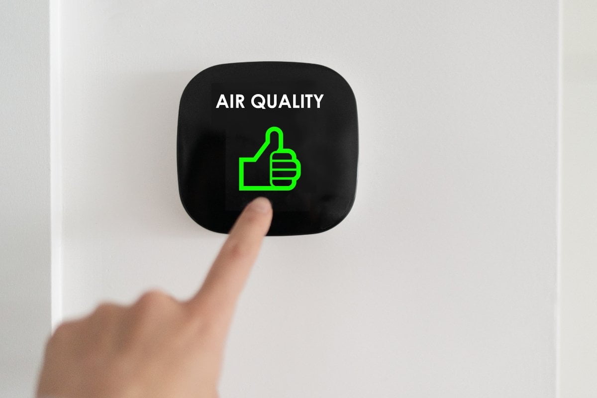 A person pressing the air quality button on a wall.