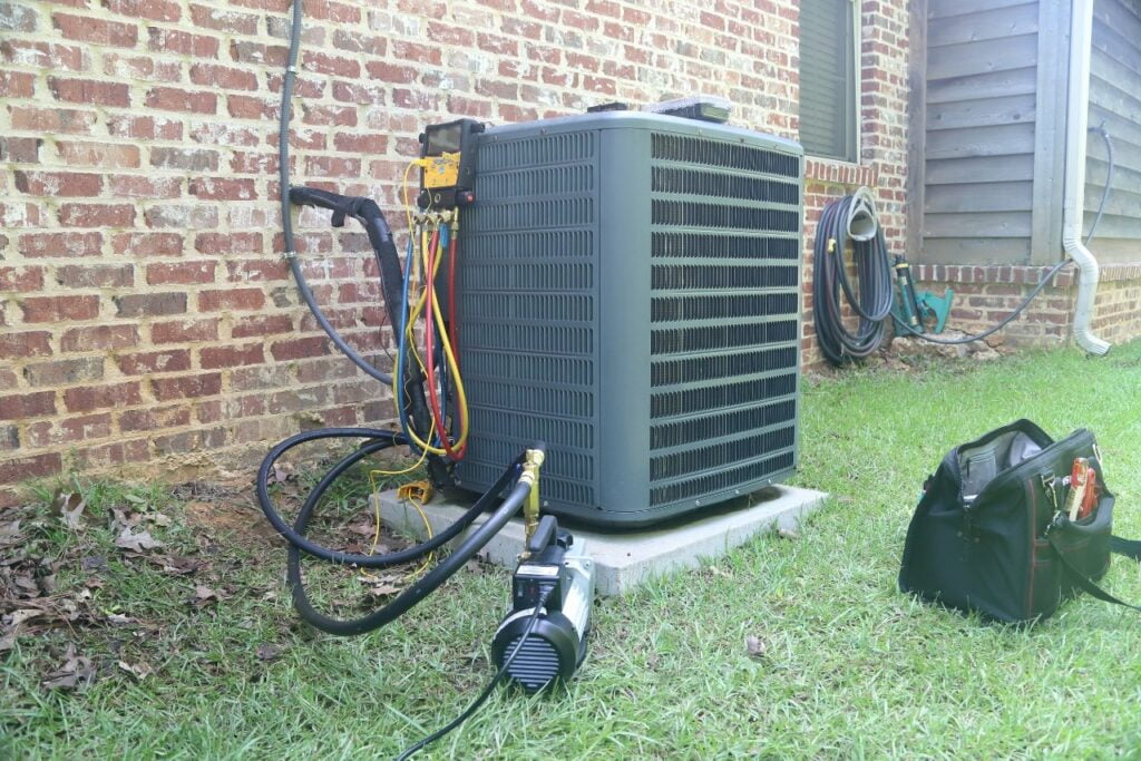 A hvac unit is sitting on the grass next to a building.