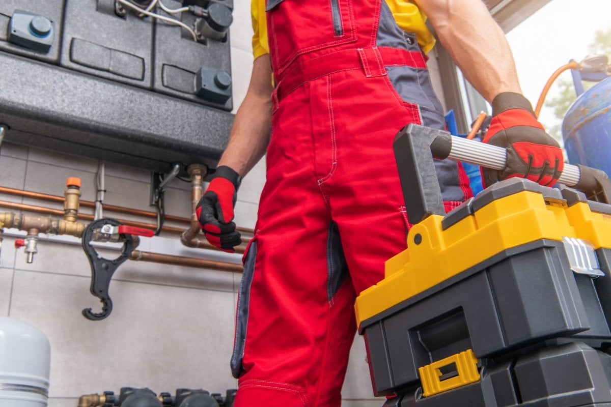 A plumber in overalls holding a toolbox.