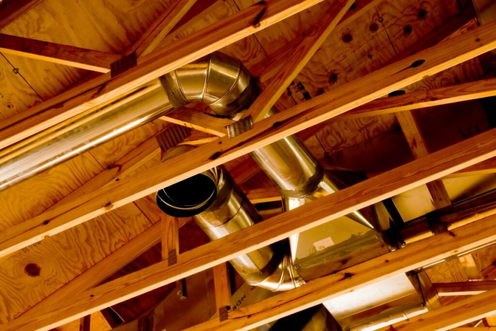 A wooden ceiling with ductwork and pipes.