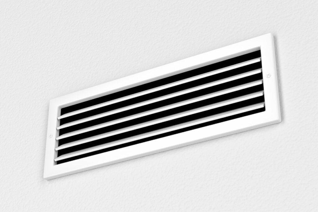 A black and white air vent on a white wall.