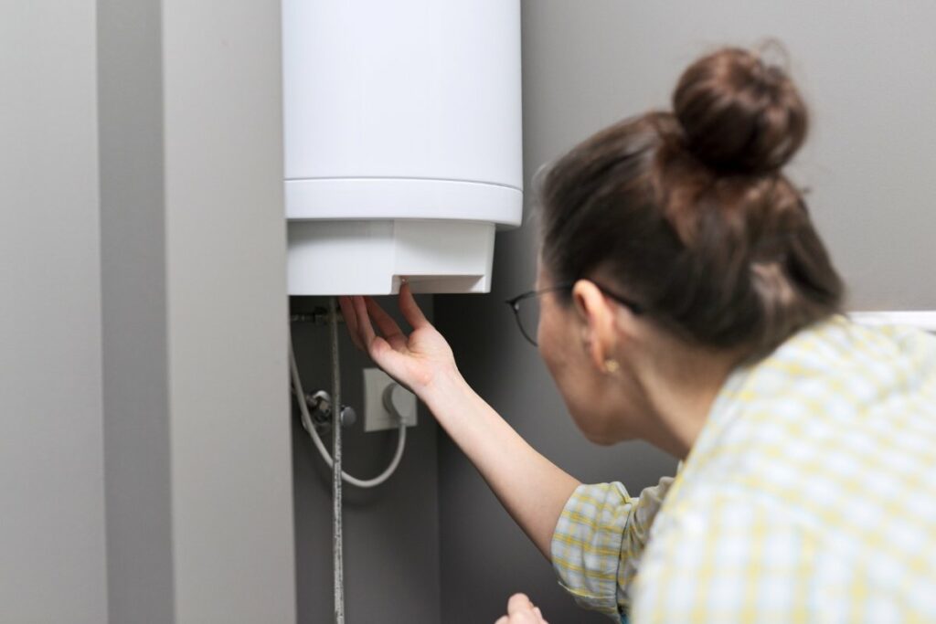 A woman looking at a water heater in a room.