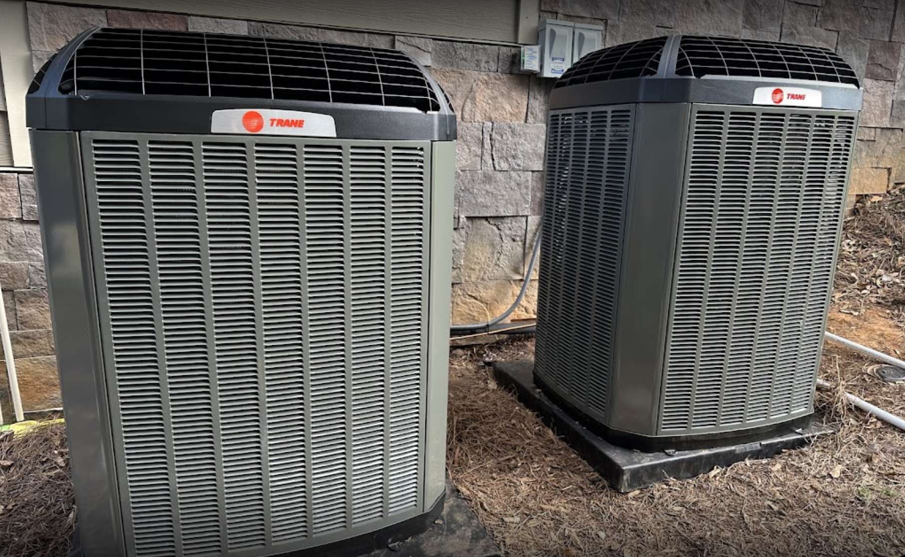 Two air conditioners in front of a house awaiting reviews.