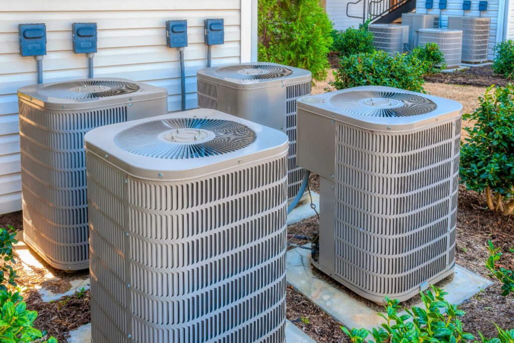 A group of air conditioners in front of a house.