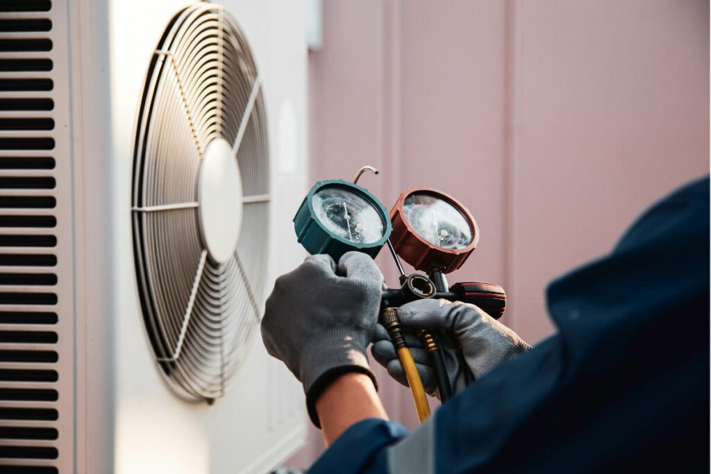 A man is holding a gauge on an air conditioner.