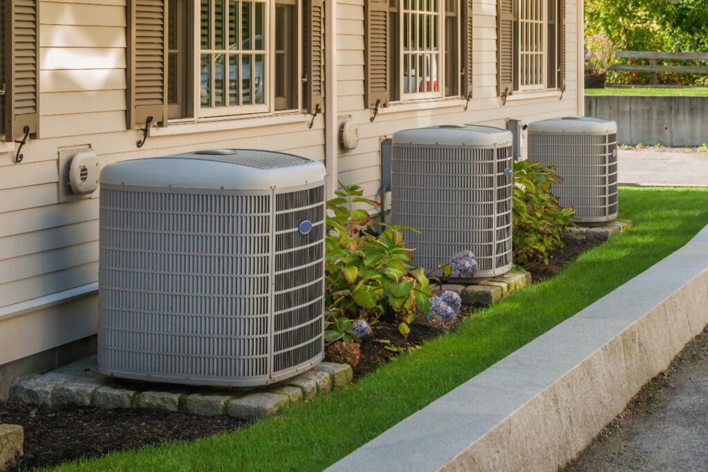 A row of air conditioners in front of a house.