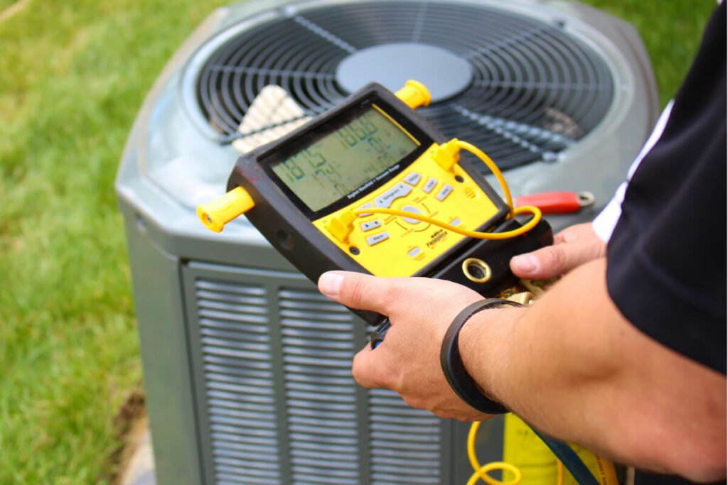 A man holding an air conditioner with a meter in front of it.