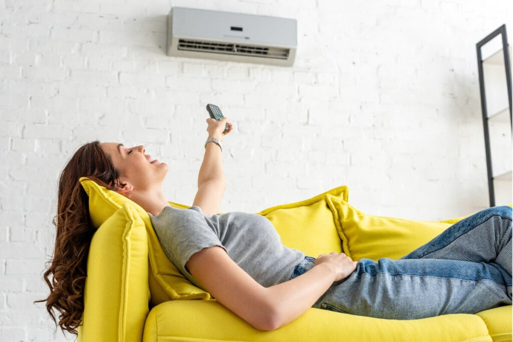 A woman relaxing on a yellow couch with a remote control.