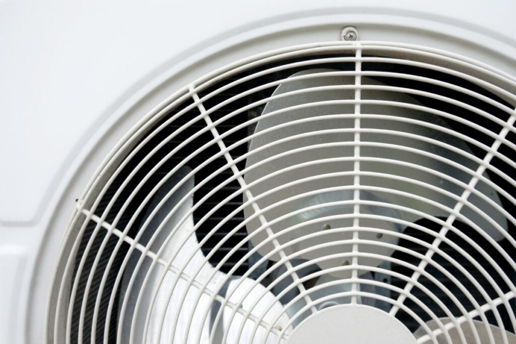 A close up of a white air conditioner with a non-operational condenser fan.