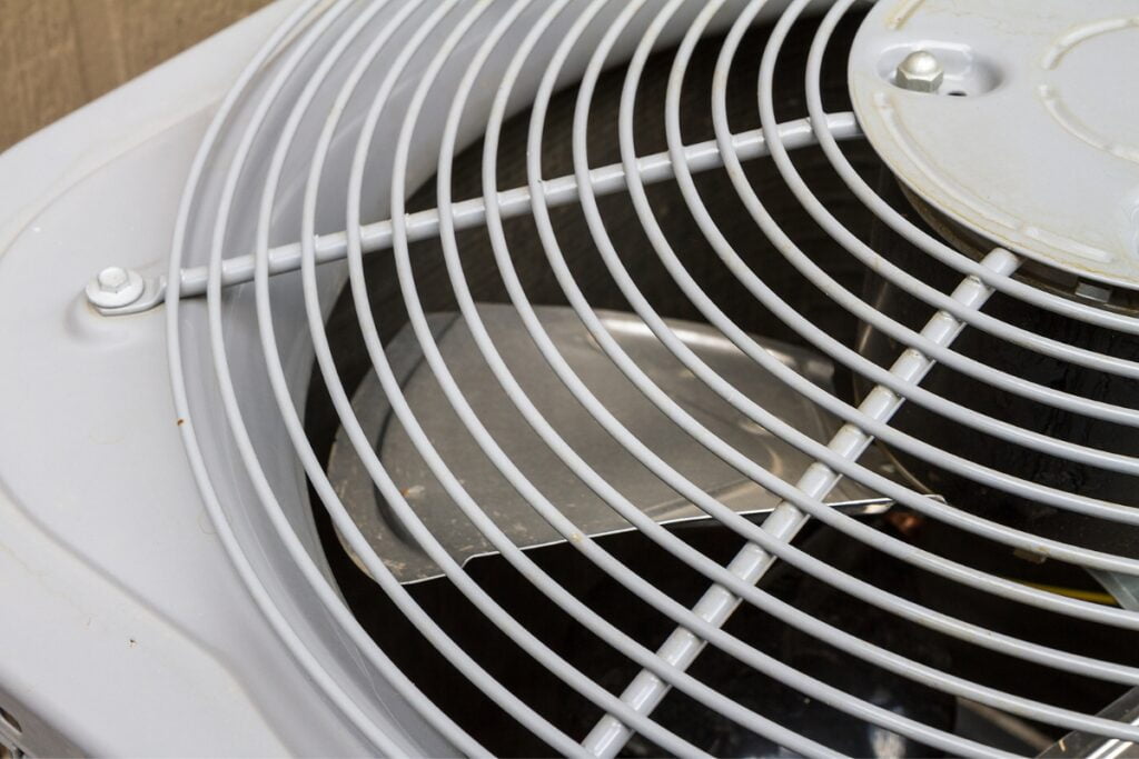 A close up of a white air conditioner with a non-functioning condenser fan.