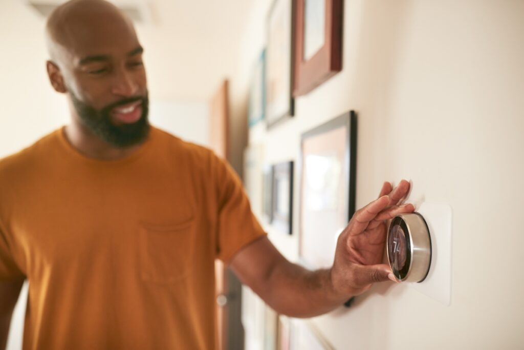 A man with a beard is holding a wireless thermostat.