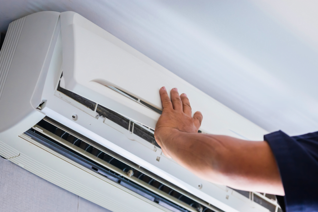 A man providing Acworth HVAC Services by fixing an air conditioner in a room.