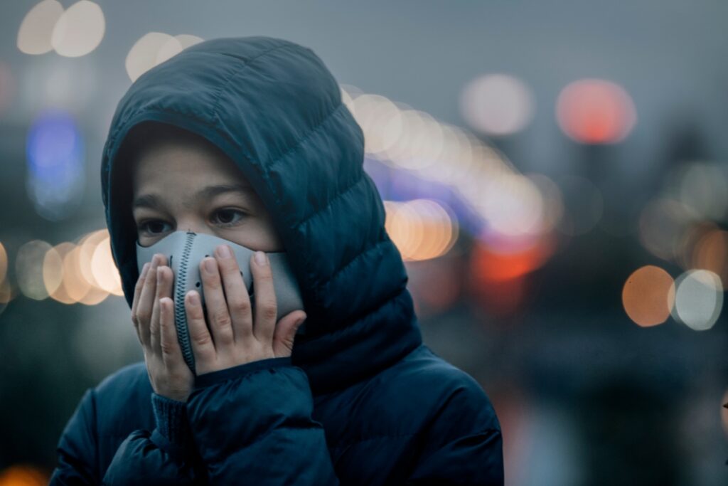 A girl wearing a face mask in a city at night, highlighting the importance of air filter maintenance.