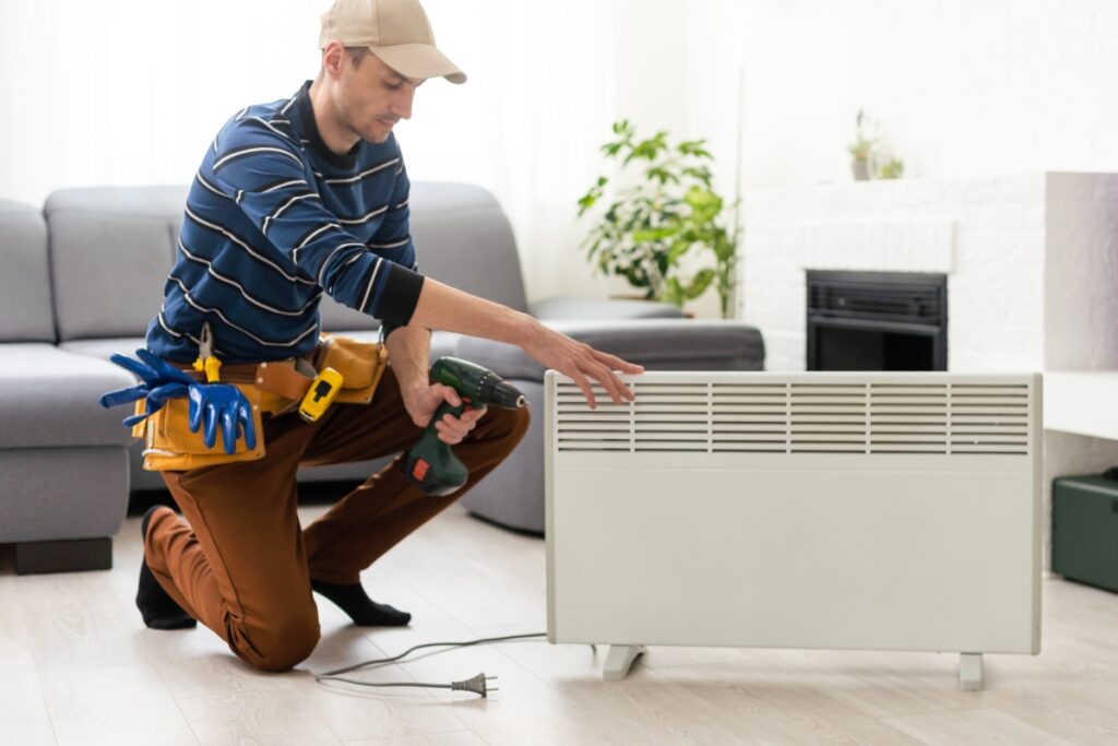 A man servicing a heater in a living room to ensure space heater safety.