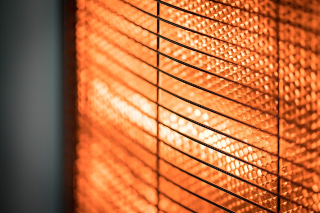 A close up image of a heater in a dark room with space heater safety tips.