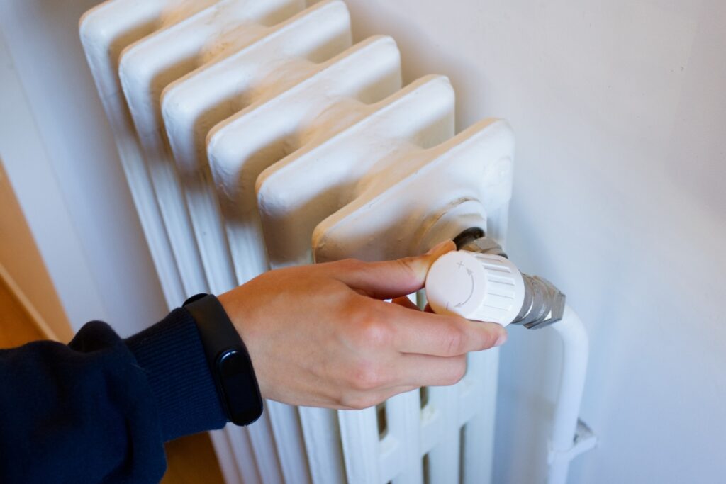 A person is putting a knob on a radiator to address the issue of losing heat in winter.