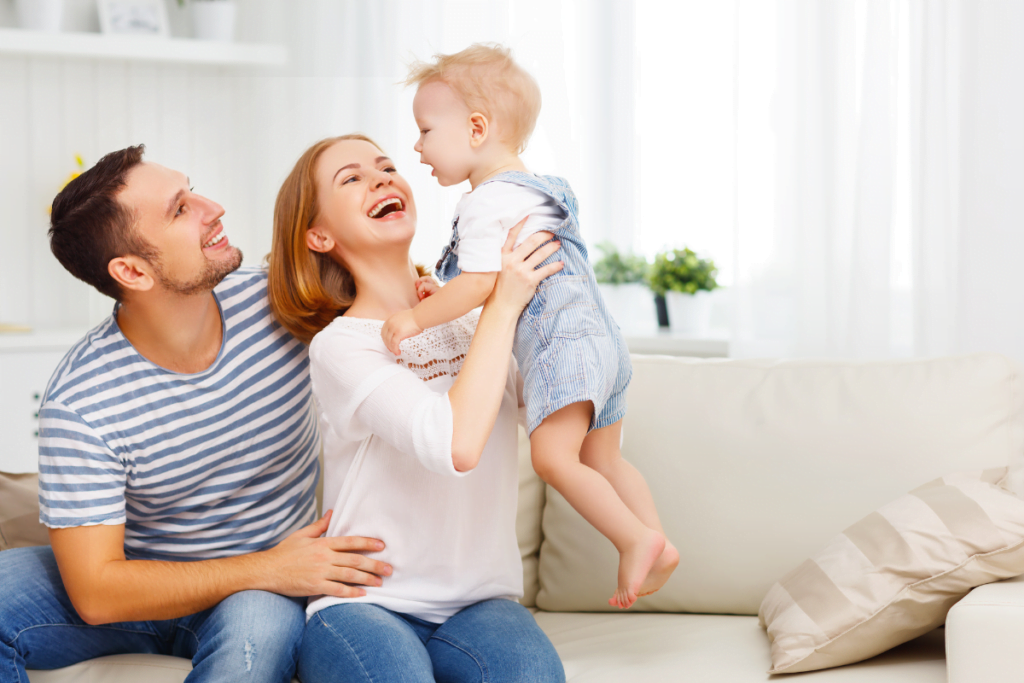 A family is sitting on a couch with a baby in their arms, enjoying a comfortable environment.