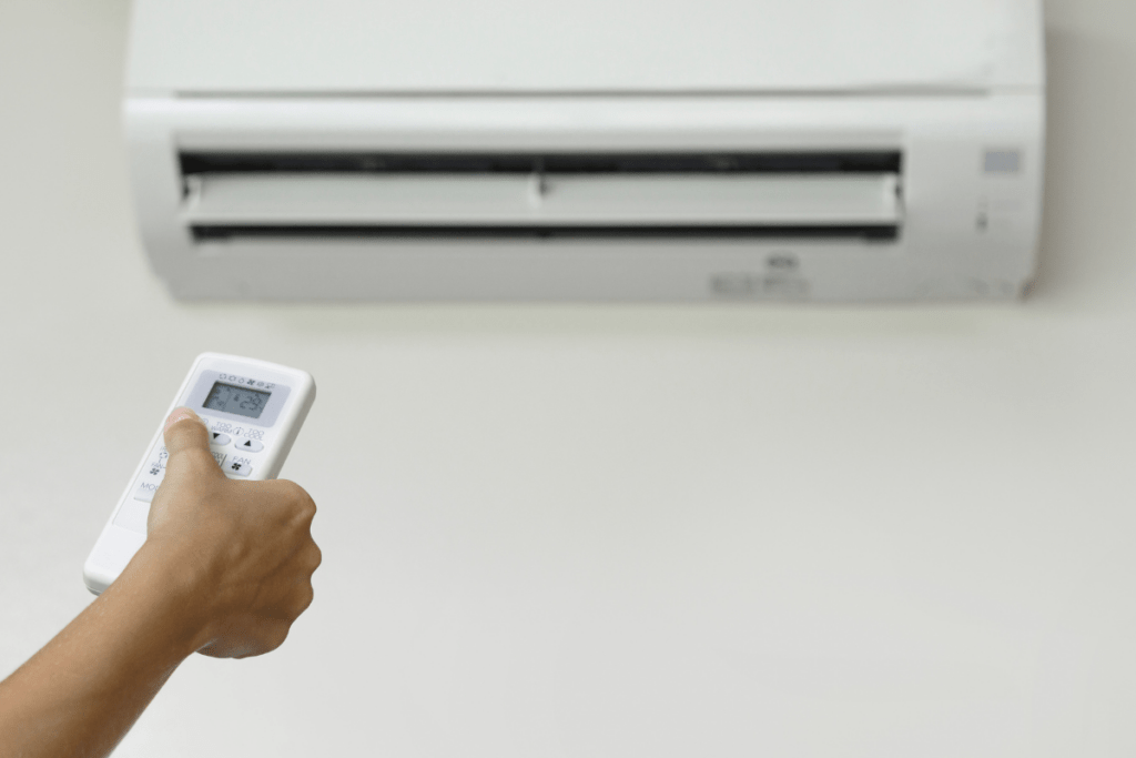 A person holding a remote control to an air conditioner, wondering what is an HVAC system.