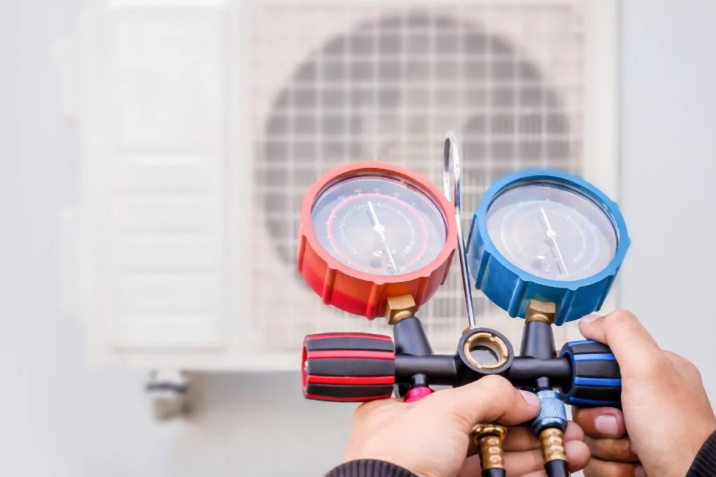 A man is assessing energy efficiency in HVAC by holding a gauge in front of an air conditioner.