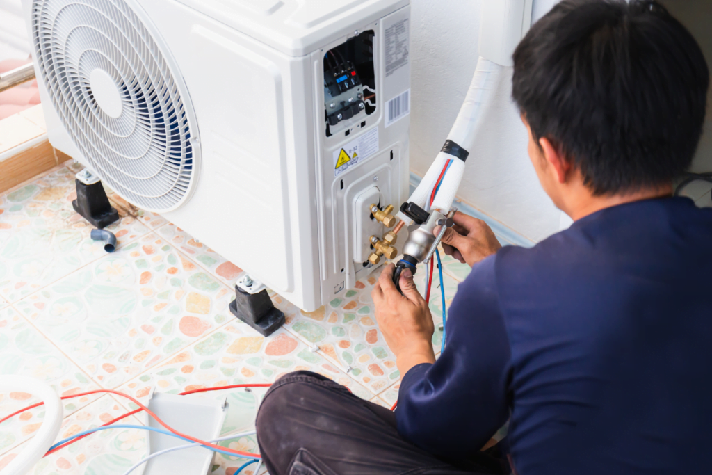 A man is performing HVAC maintenance on an air conditioner.