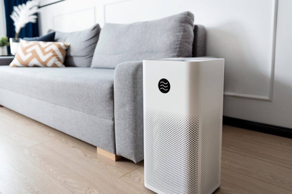 A white rectangular object, possibly an air purifier, next to a couch.