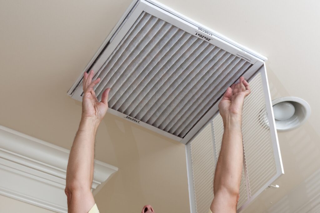 A man is holding up an air conditioner in a room, ensuring optimal indoor air quality.