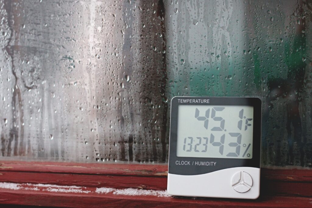 A digital thermometer measuring indoor air quality, sitting on a window sill.