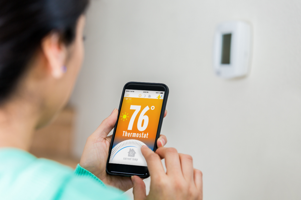 A woman controlling her smart thermostat from her phone.