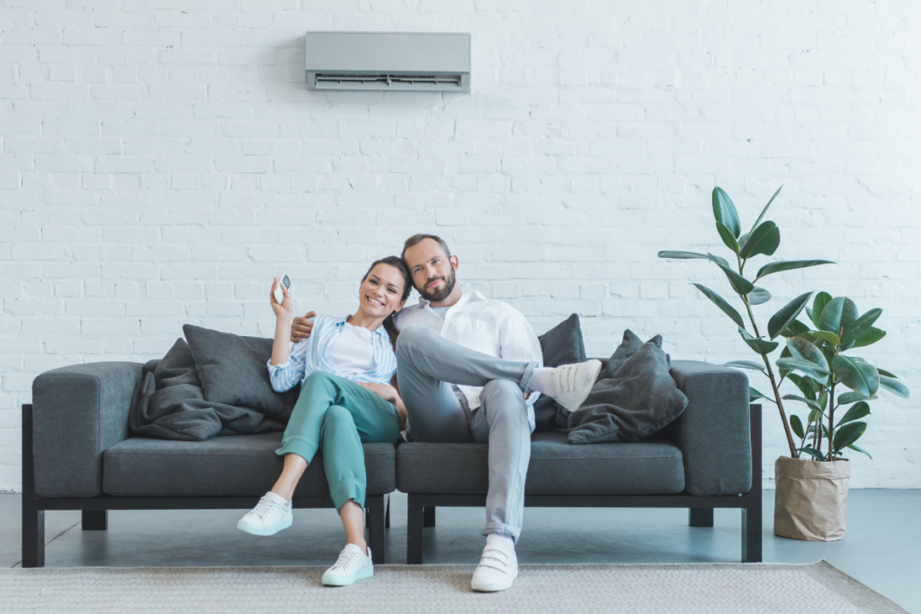 A man and woman sitting on a couch, enjoying the indoor air.