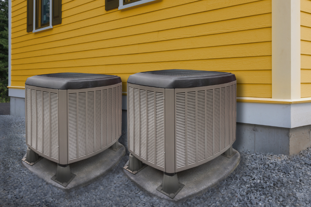 Two air conditioners getting ready for summer in front of a yellow house.