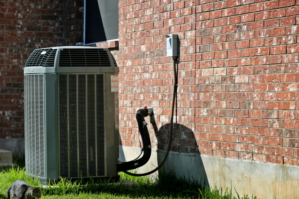 An outdoor unit of a central air system outside a brick building.