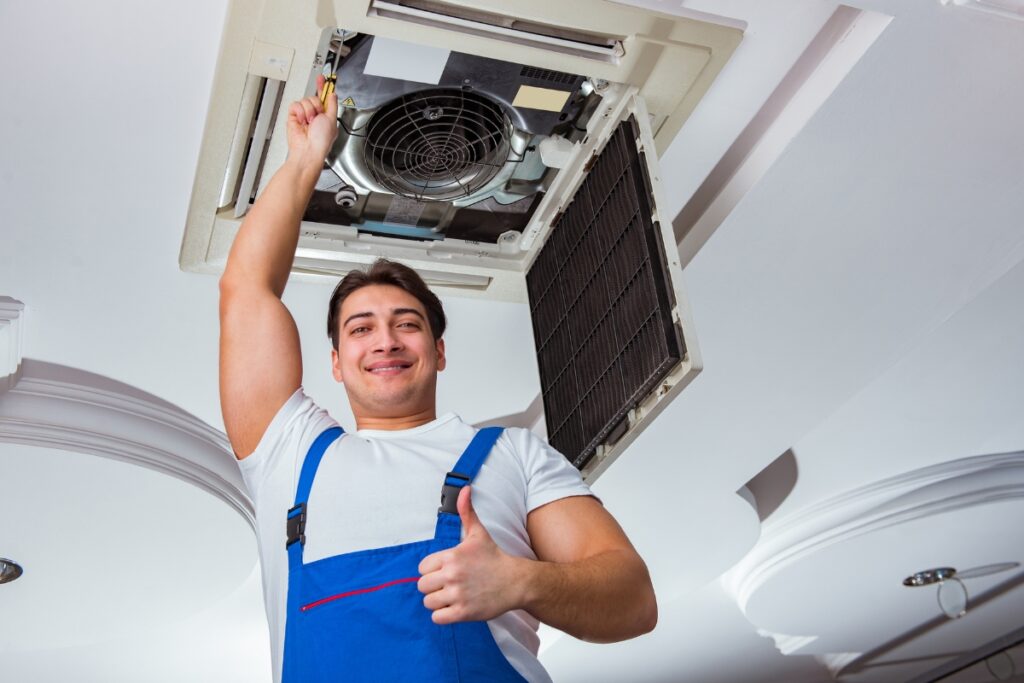 Technician giving a thumbs-up while servicing an HVAC system upgrade.