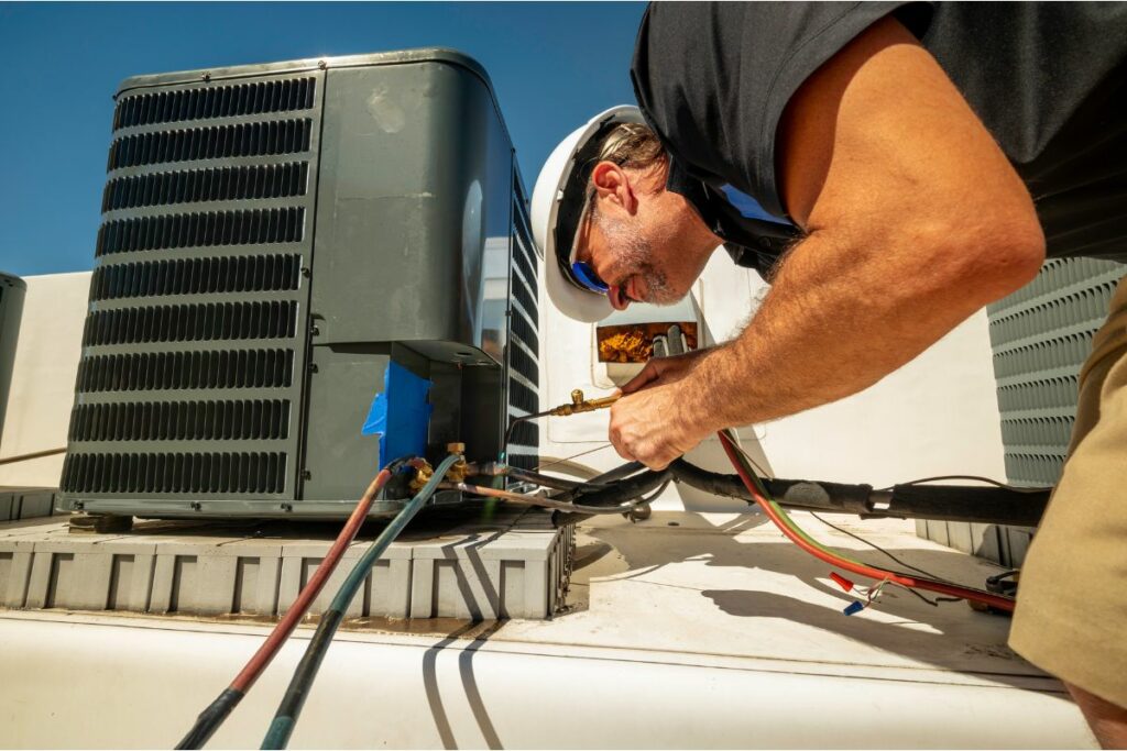 A technician conducts an HVAC system analysis on an outdoor air conditioning unit on a sunny day, using tools to adjust components.