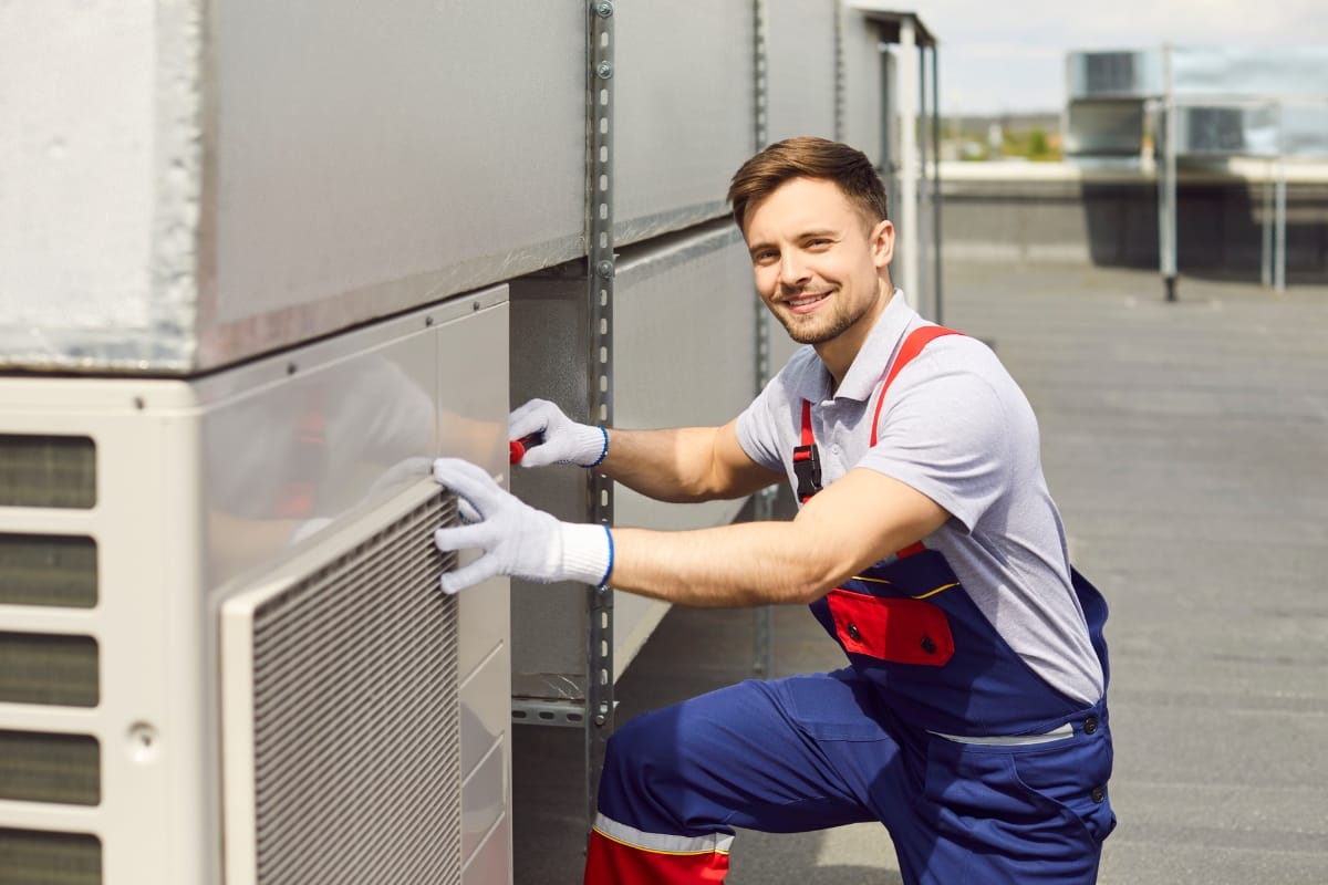 A technician in uniform and gloves conducts a thorough HVAC inspection on a rooftop, ensuring optimal performance crucial for real estate value.